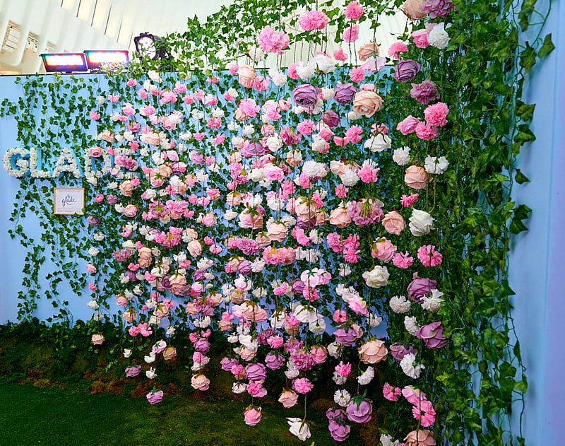 Custom floral logo lettering on a hanging artificial flower and ivy wall at a brand activation