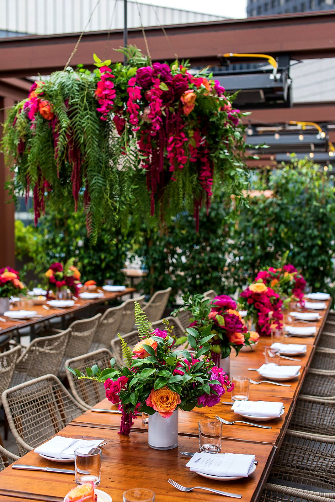 Hanging floral chandelier and bright centerpieces over a long restaurant table